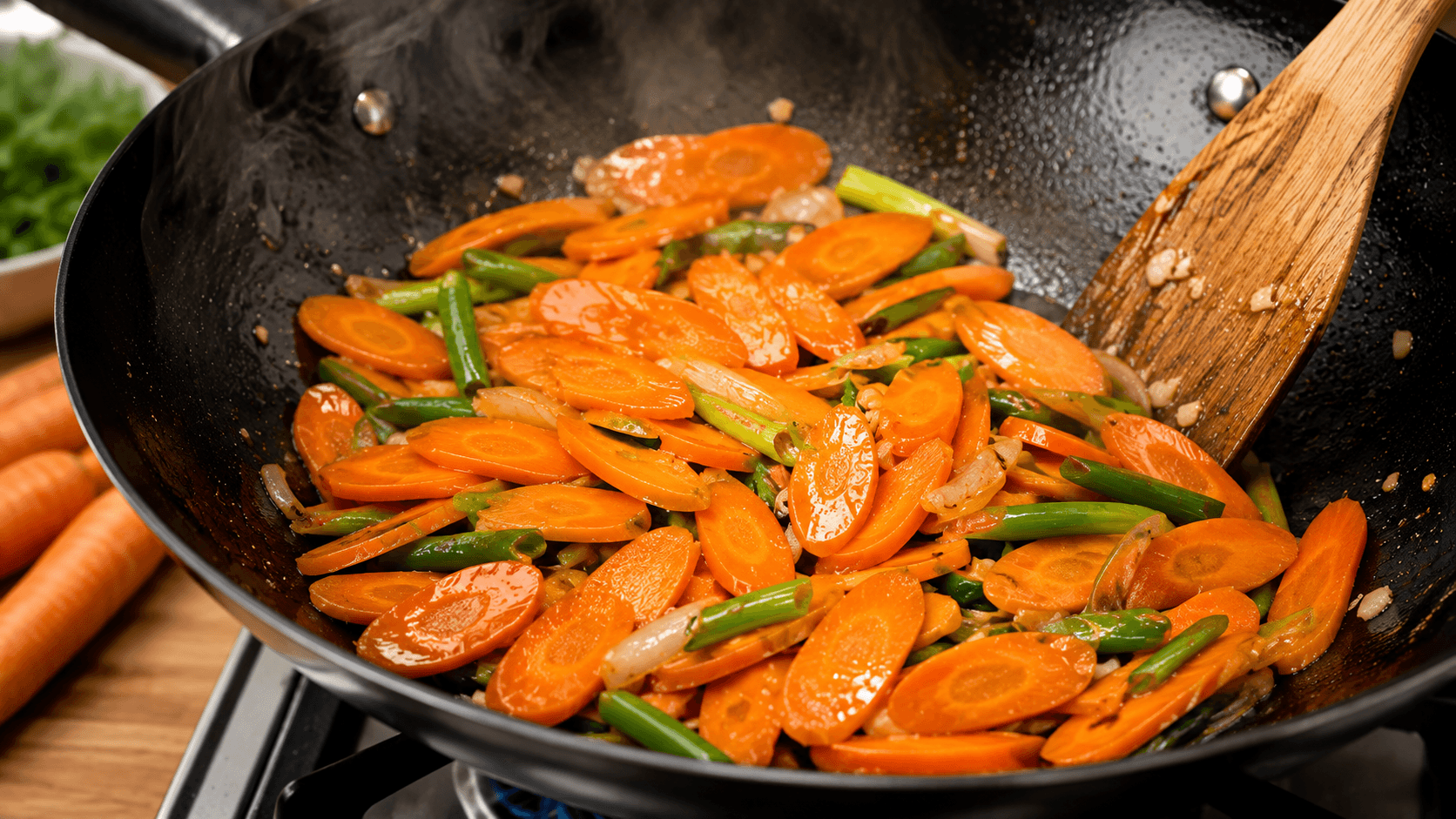 Thinly sliced carrots cooking in a hot wok until crisp-tender for chicken stir fry