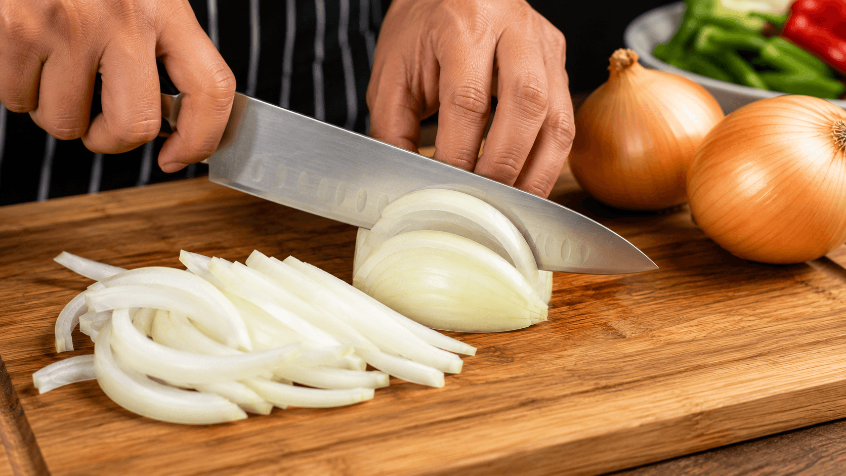 Slicing onions with a sharp chef's knife into even strips for stir fry preparation