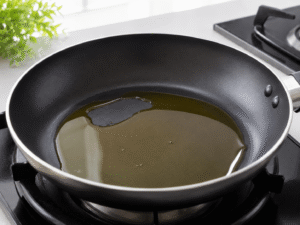 Olive oil heating in a black nonstick frying pan on a gas stove in a bright modern kitchen setting.
