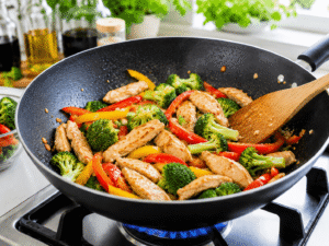 Chicken stir fried with sliced bell peppers and broccoli florets until tender-crisp in a black wok.