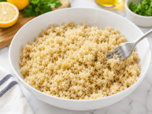 Fluffy cooked quinoa in a serving bowl being gently fluffed with a fork