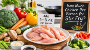 Raw sliced chicken breast measured for the ideal chicken per person stir fry serving size with fresh vegetables on a kitchen counter